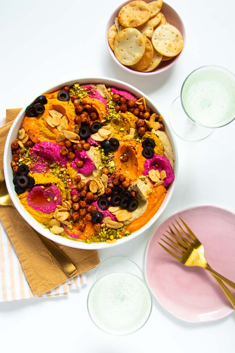 Dollops of hummus topped with a variety of toppings and served with sparkling wine and pita chips.