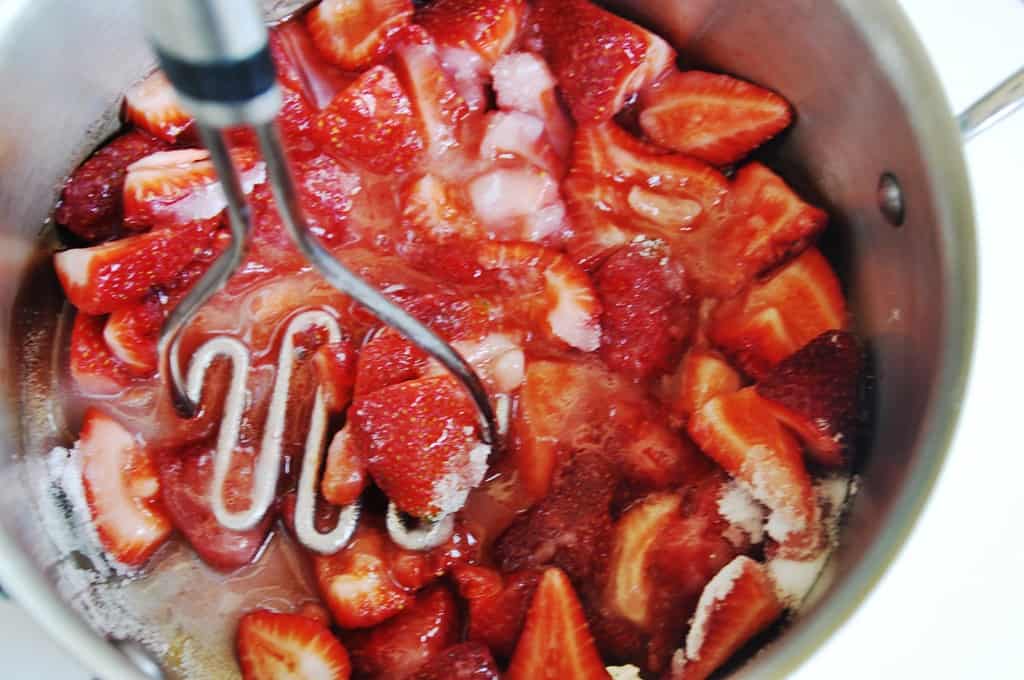 Mashing strawberries over medium heat 