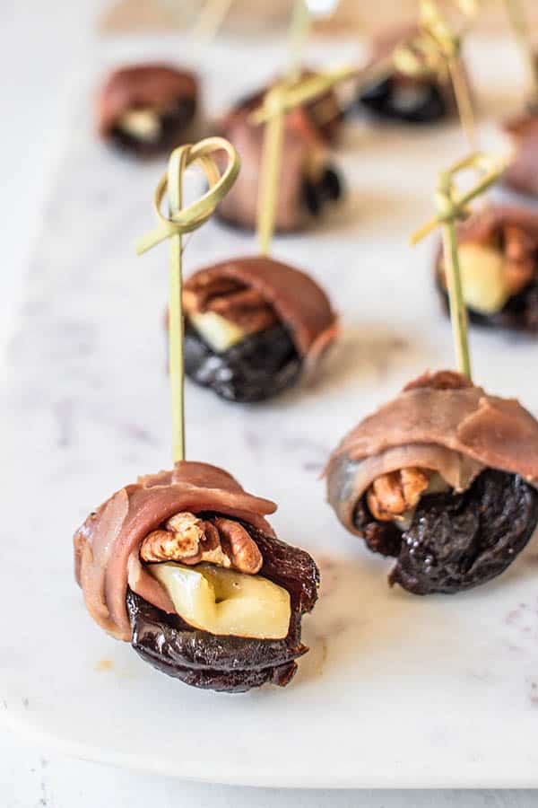 Prosciutto Wrapped Prunes on a marble serving board. 