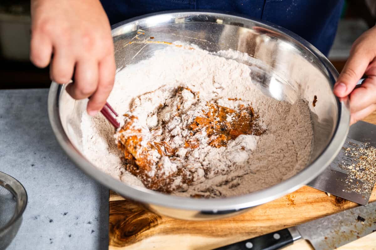 mixing the wet and dry ingredients together to make pumpkin muffins