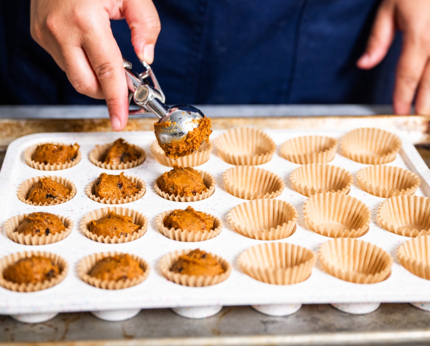 scooping pumpkin muffins into muffin pan