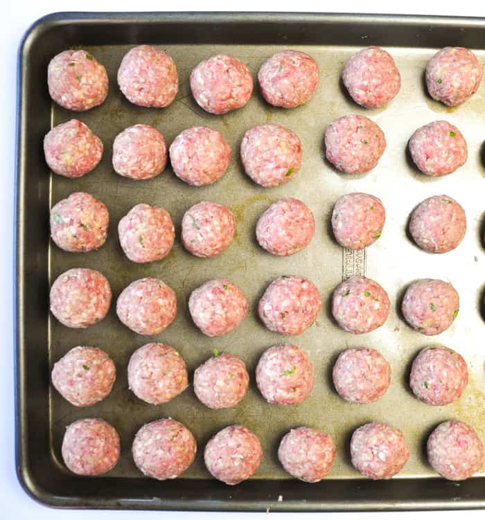Meatballs rolled into consistent sized balls on baking sheet