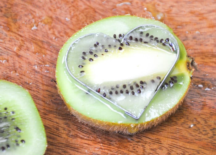Heart shaped cookie cutter placed on kiwi, lengthwise 