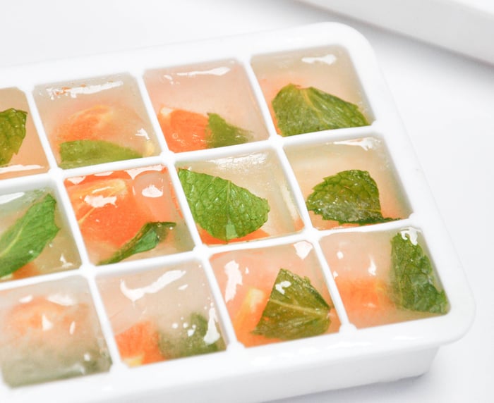 Frozen citrus and mint in ice cube tray