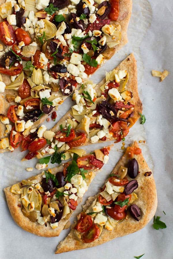 A mediterranean flatbread with artichokes, slices and roasted red peppers.