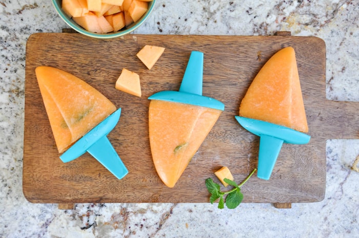 Minty Cantaloupe Popsicles laying on serving tray with a sprig of mint