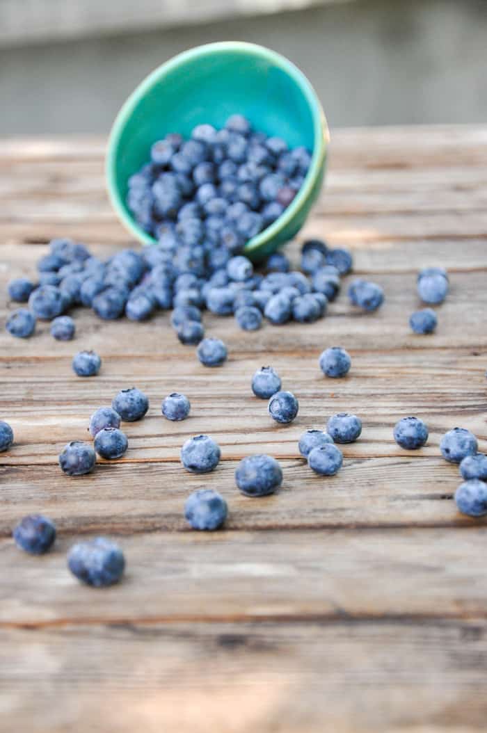 Blueberries spilling out of bowl onto table