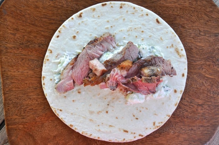 Tortilla with cucumber spread topped with sliced lamb shoulder chop