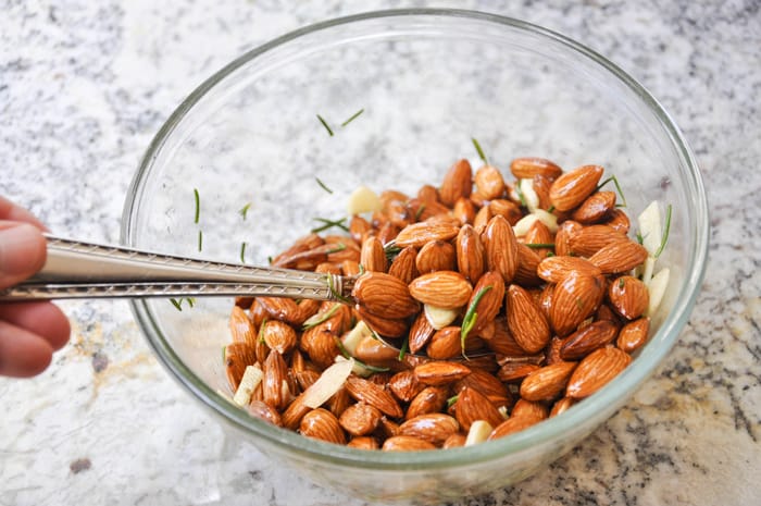 Mixing olive oil, rosemary, almonds, seat salt, and garlic together in a bowl 