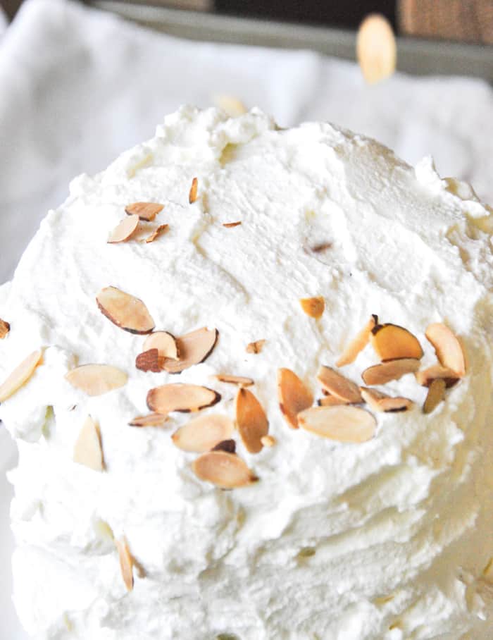Sprinkle almond slices onto whipped cream 