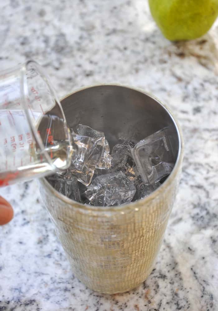 Pouring vodka in cocktail shaker over ice