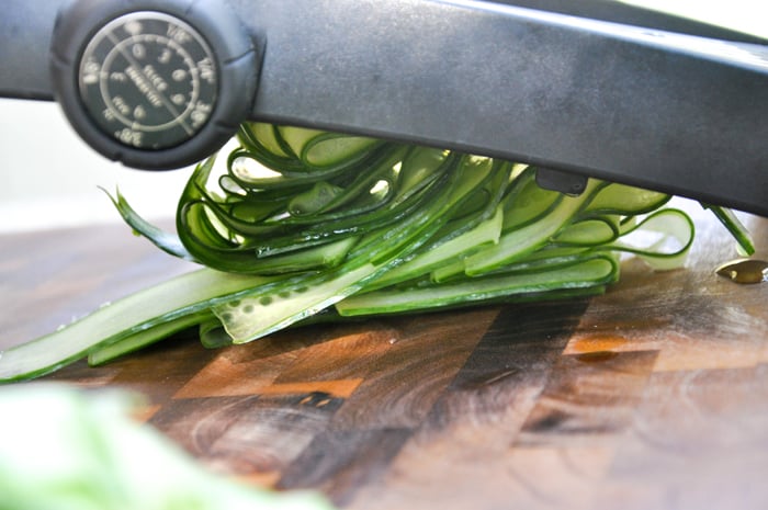 Cucumber's being cut with a mandoline to make ribbons