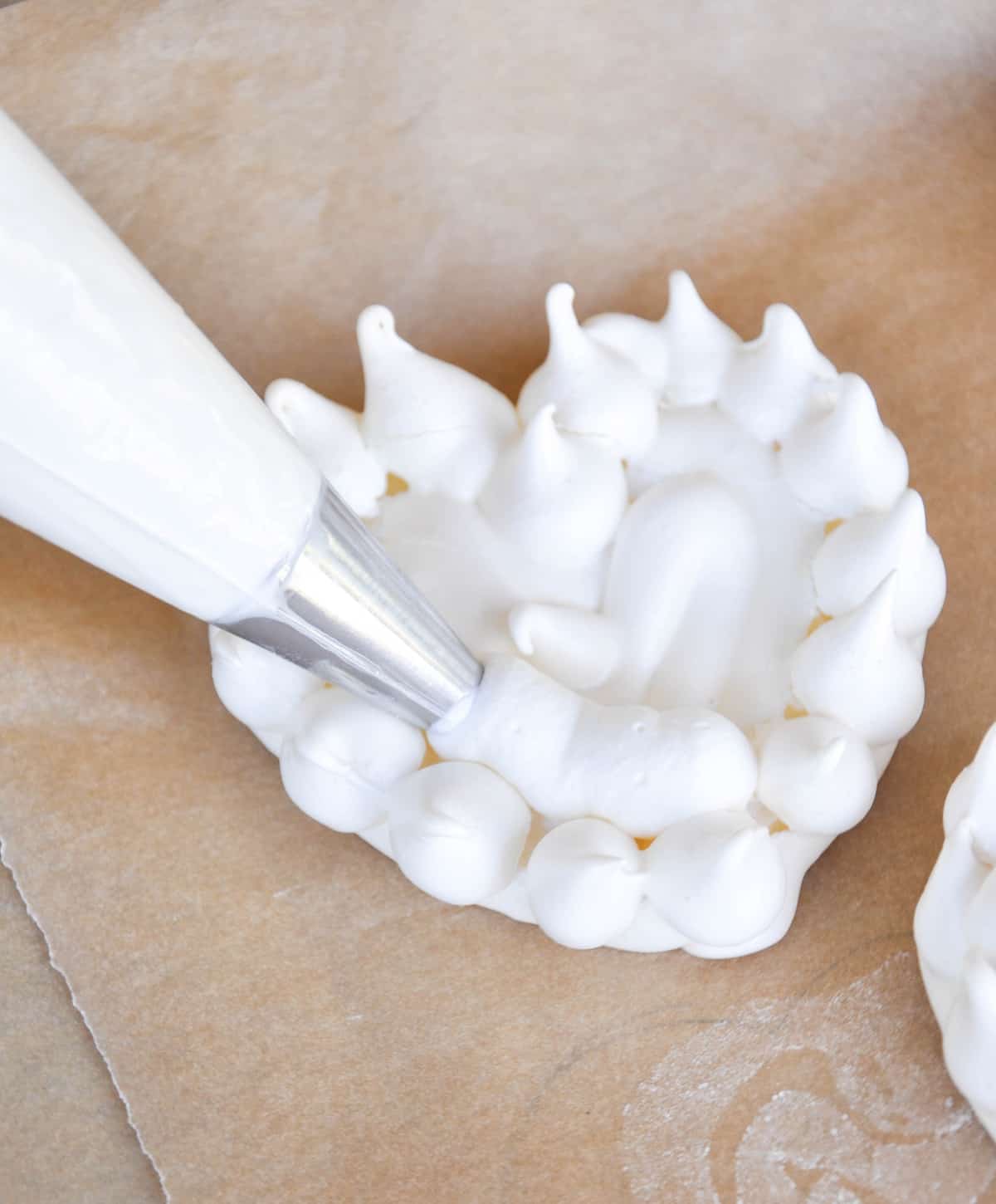 Whipped cream being added to center of baked meringue