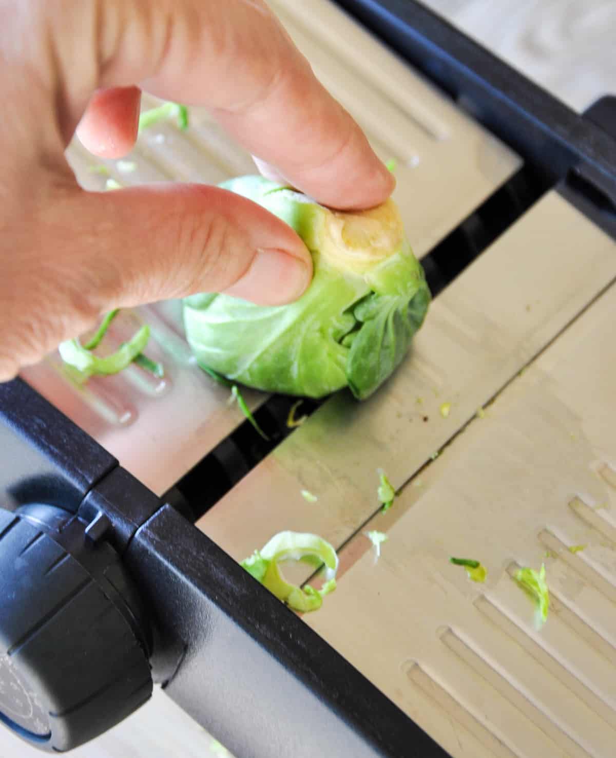 Slicing a brussels sprout with a mandoline 