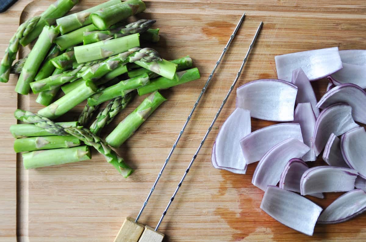 Onion and asparagus cut next to skewer 
