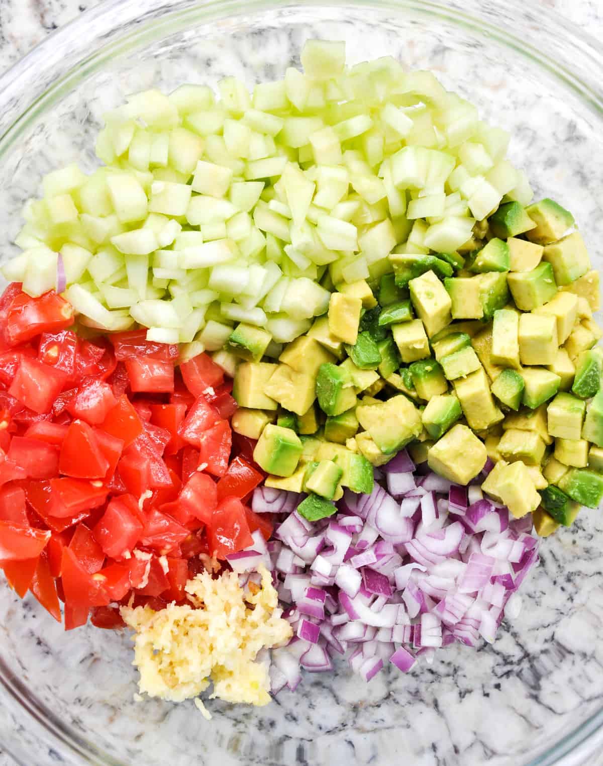 Ingredients diced up: cucumber, tomato, red onion, garlic and avocado