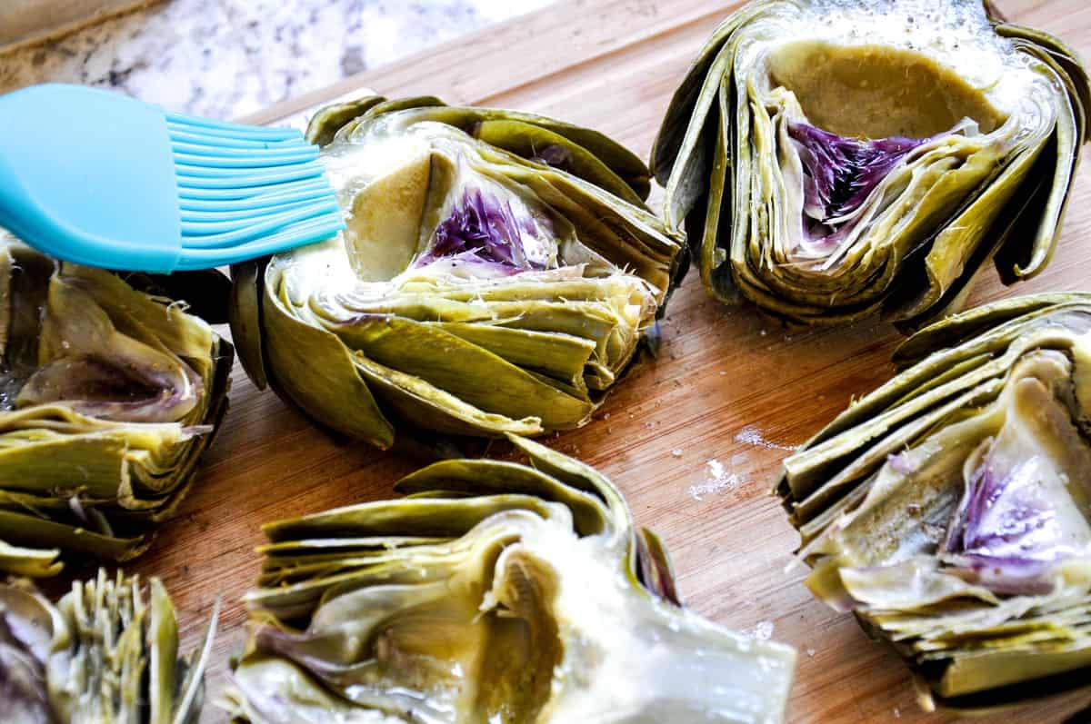 Applying olive oil on Artichokes