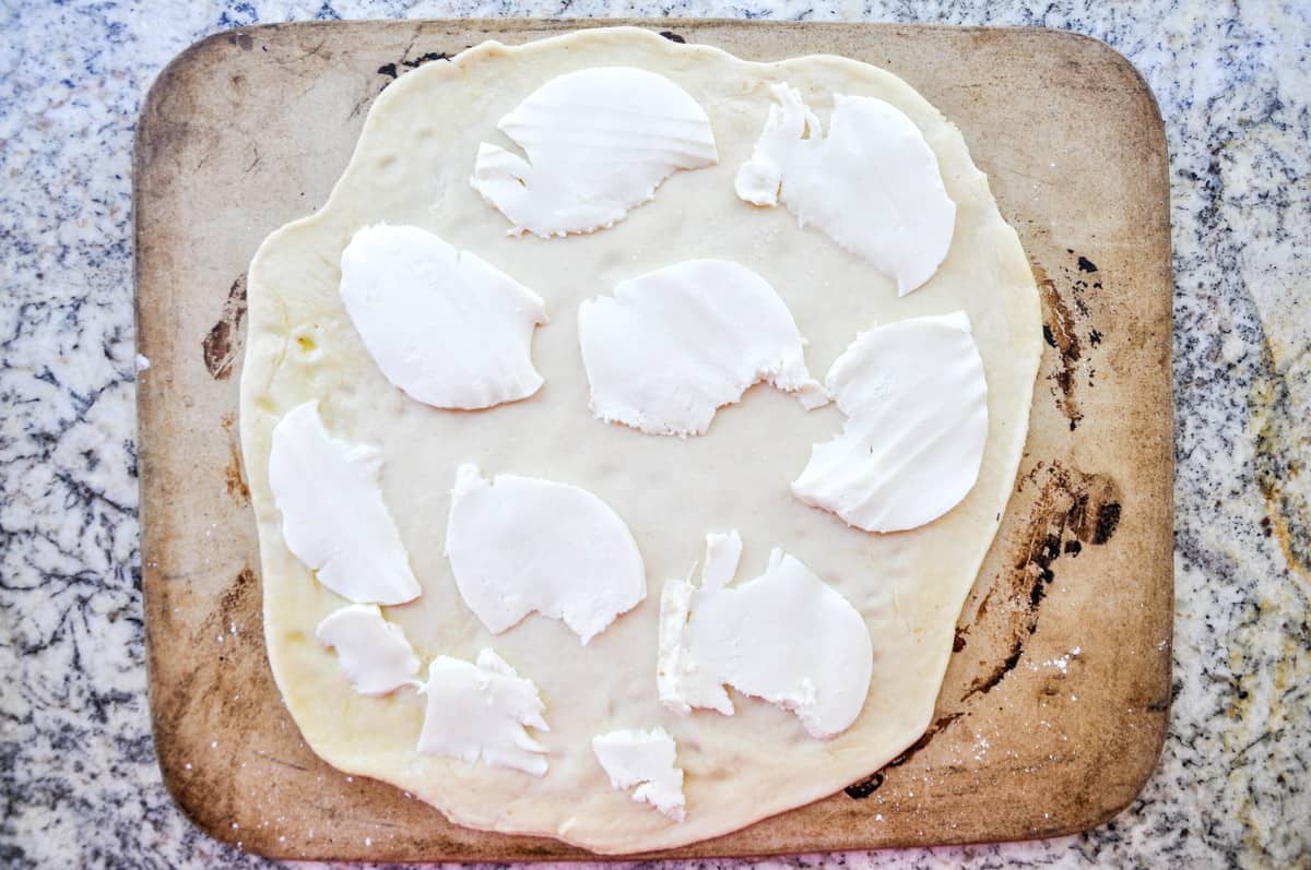 Mozzarella cheese placed over pizza dough 