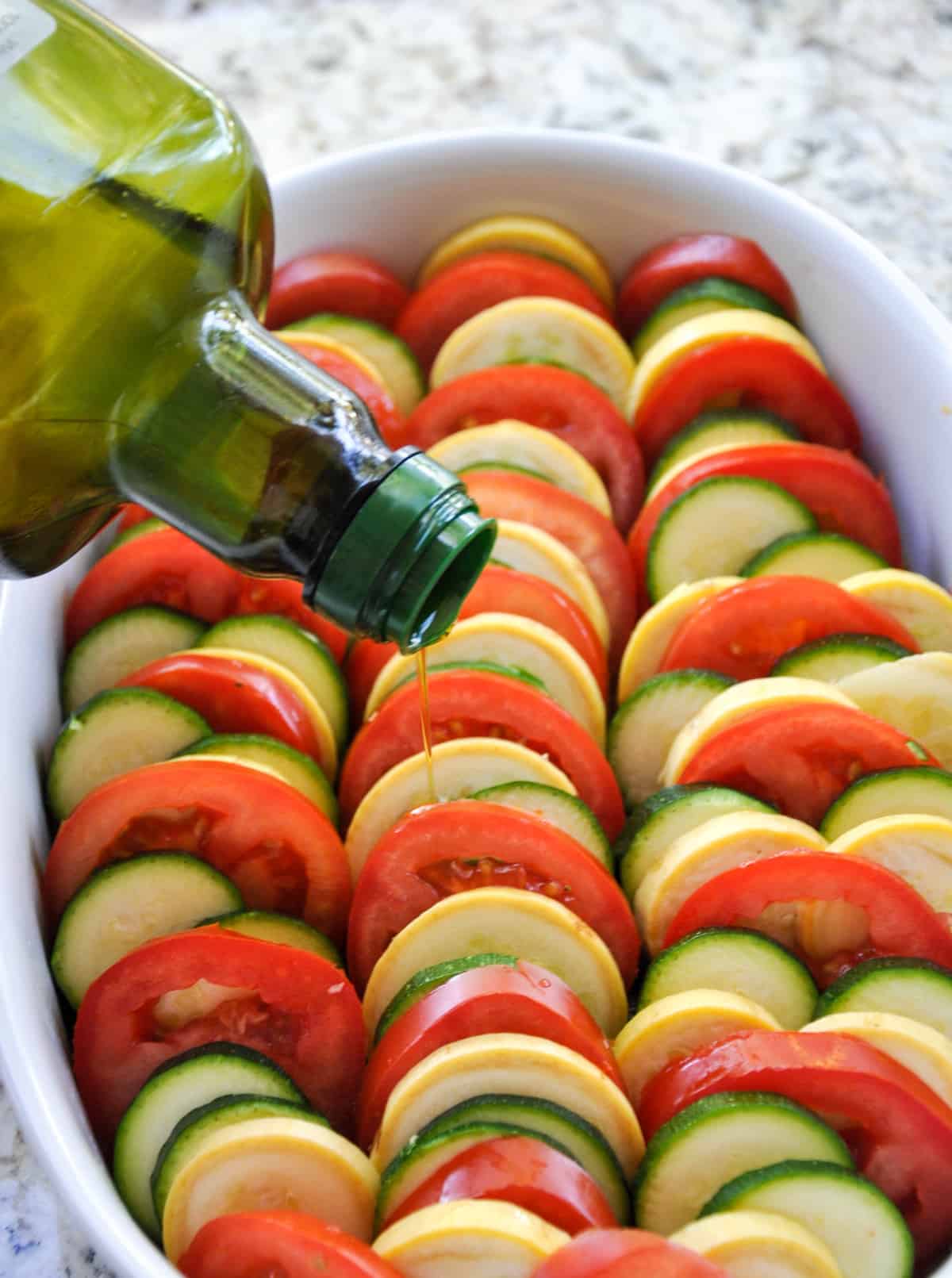 Drizzle olive oil over layered zucchini and tomatoes 