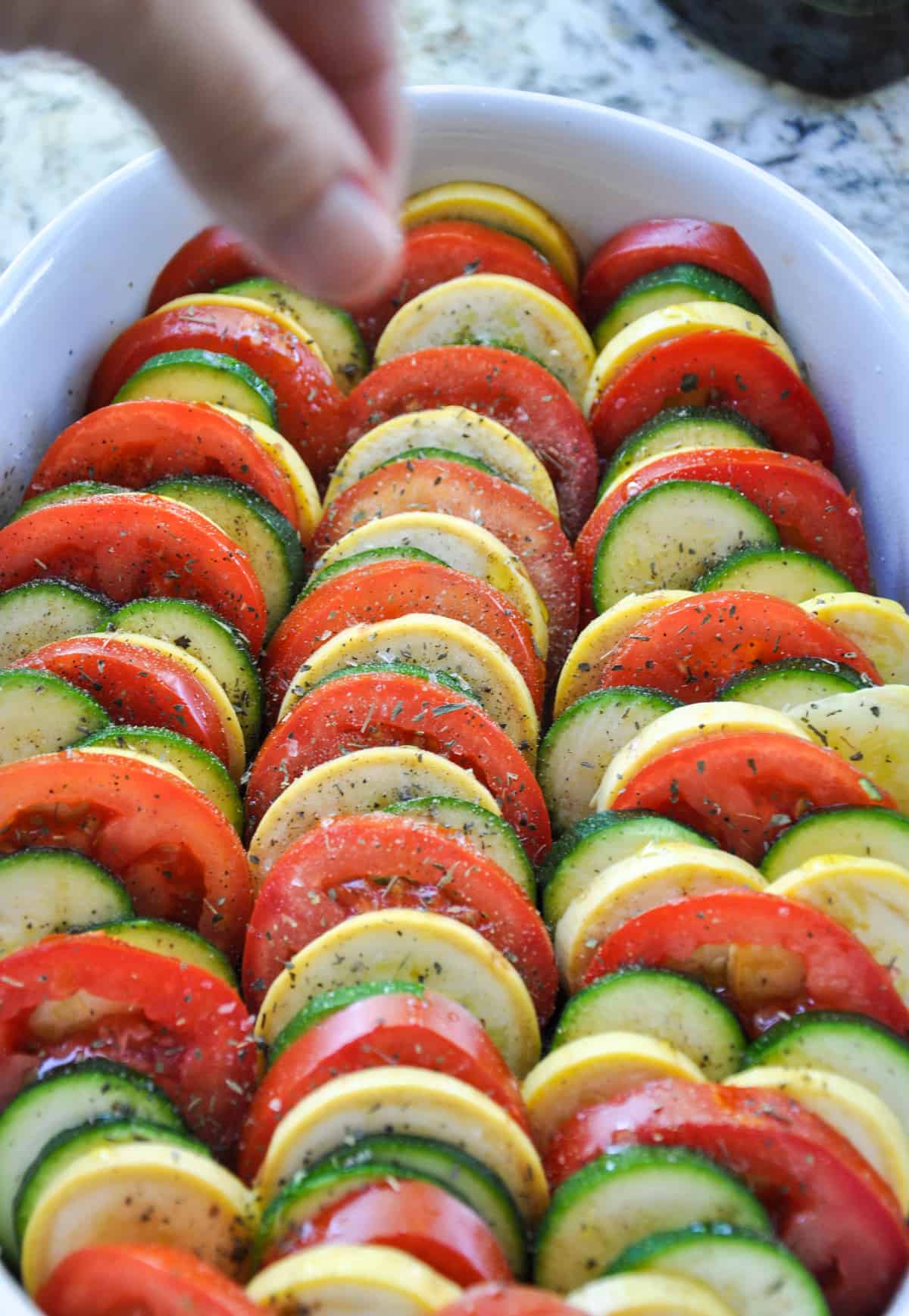 Sprinkle dried basil over layered zucchini and tomatoes 