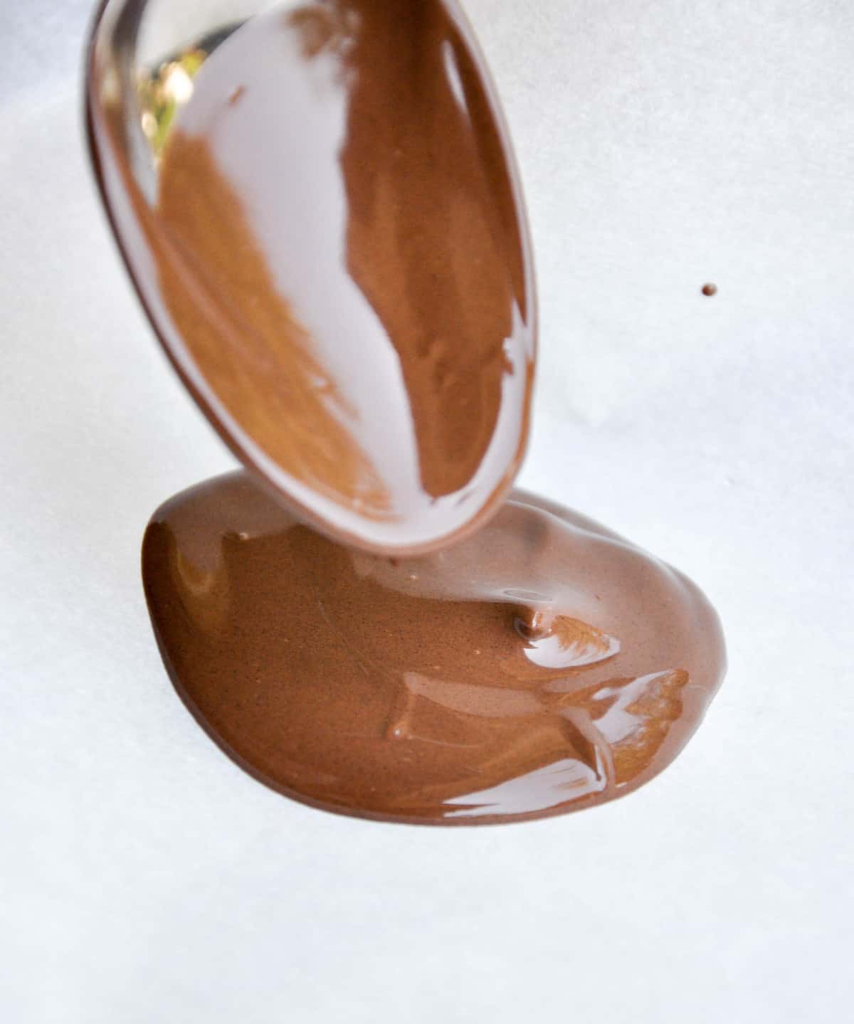 melted dark chocolate being spooned into circles 