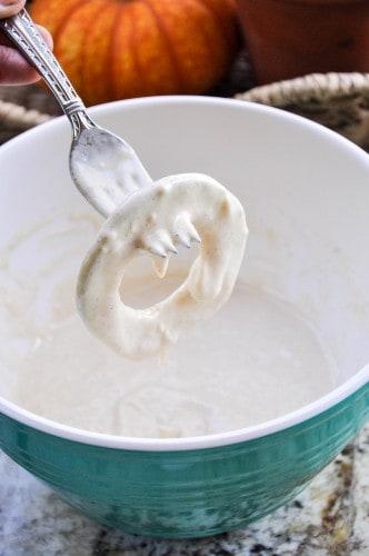 An apple ring being dipped in batter for fried apples.