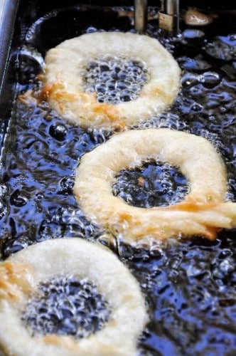 Fried apple rings being cooked in hot oil.