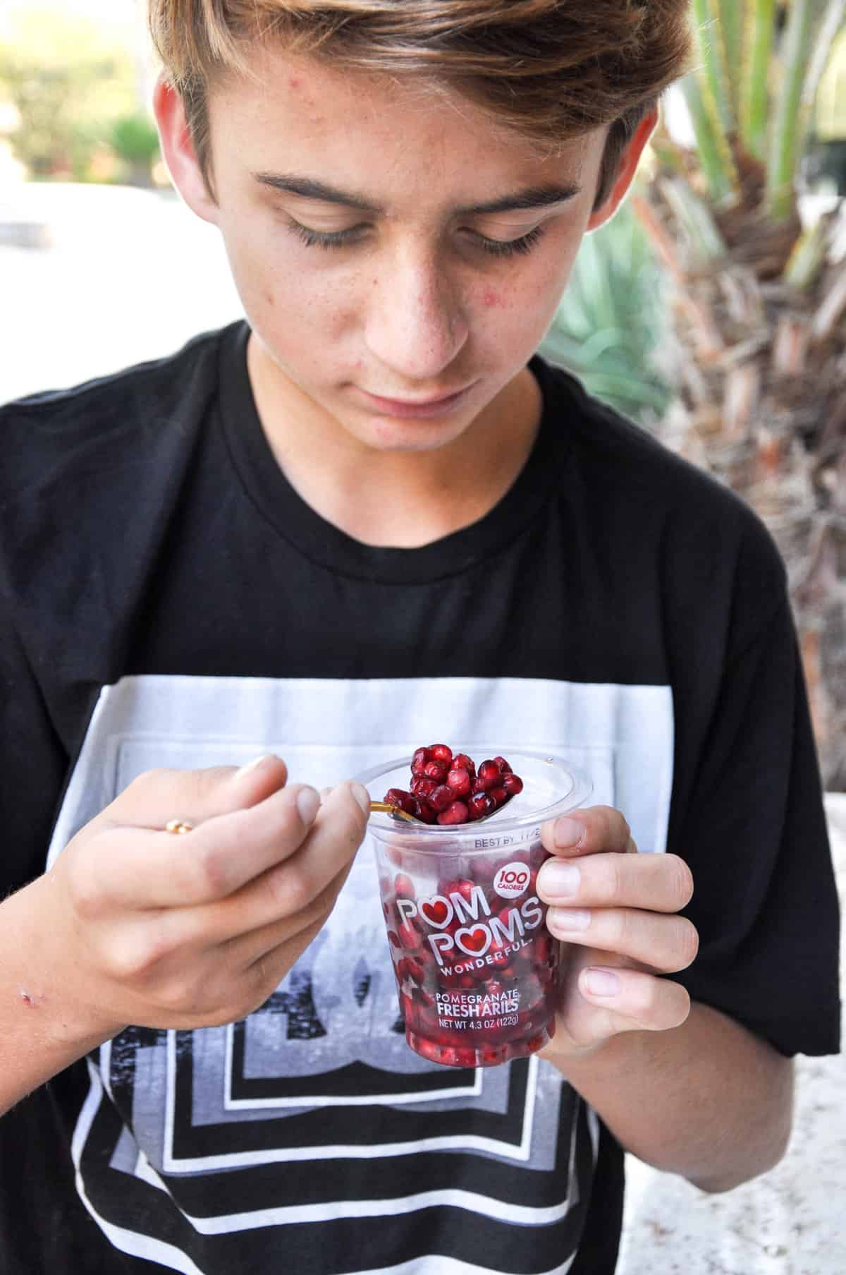 Child eating pomegranates out of Pom Poms container 
