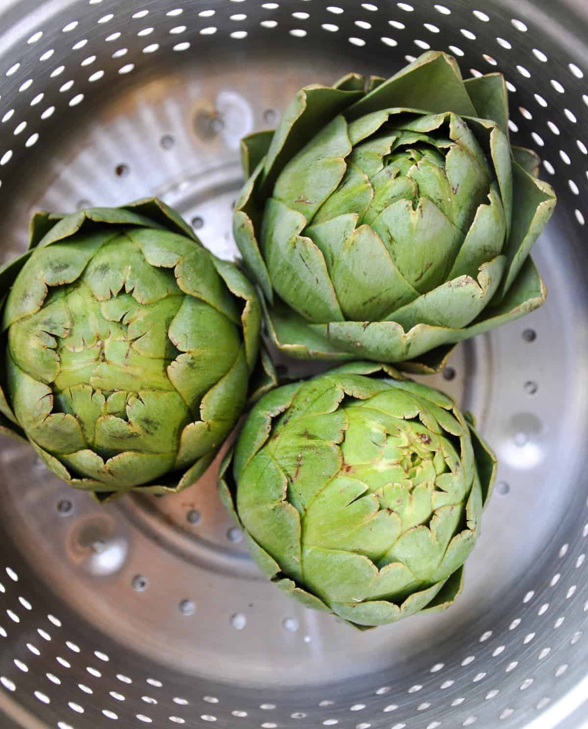 Three artichokes in strainer