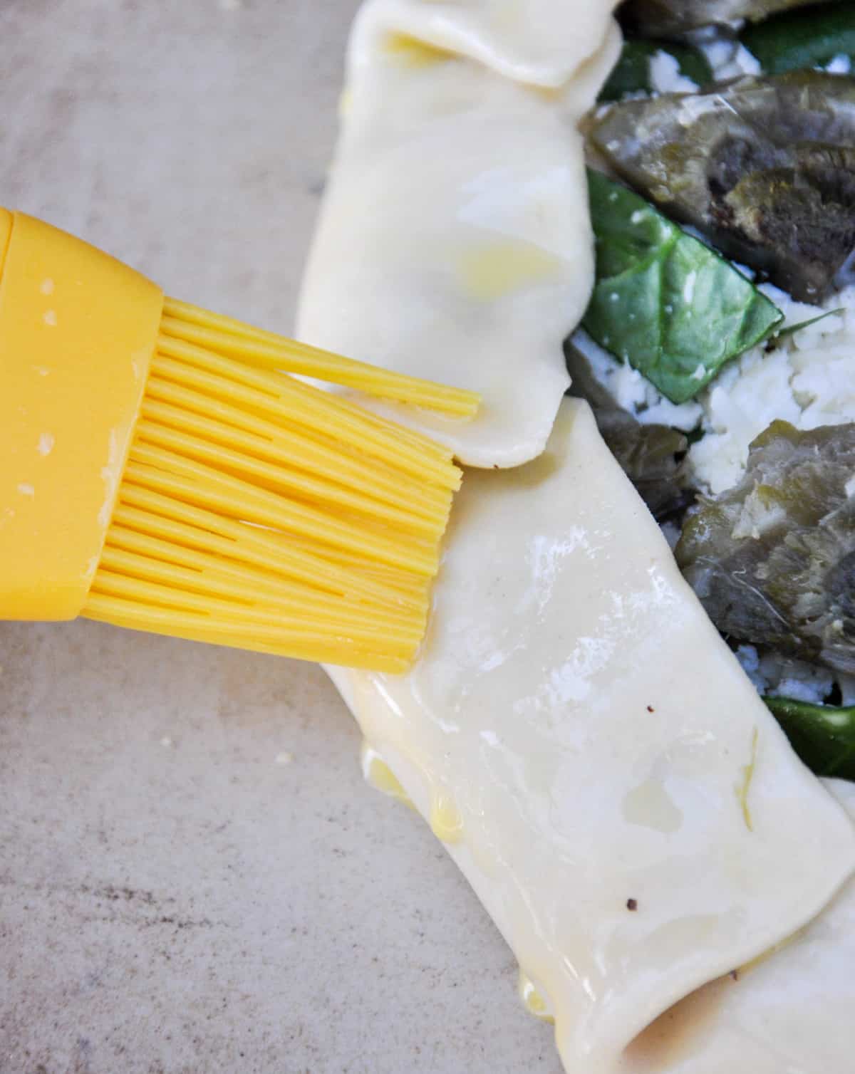 Brush egg wash over pie crust dough on a savory galette