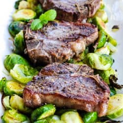 Lamb Loin Chops recipe on a platter with roasted brussels sprouts and a mustard mint sauce