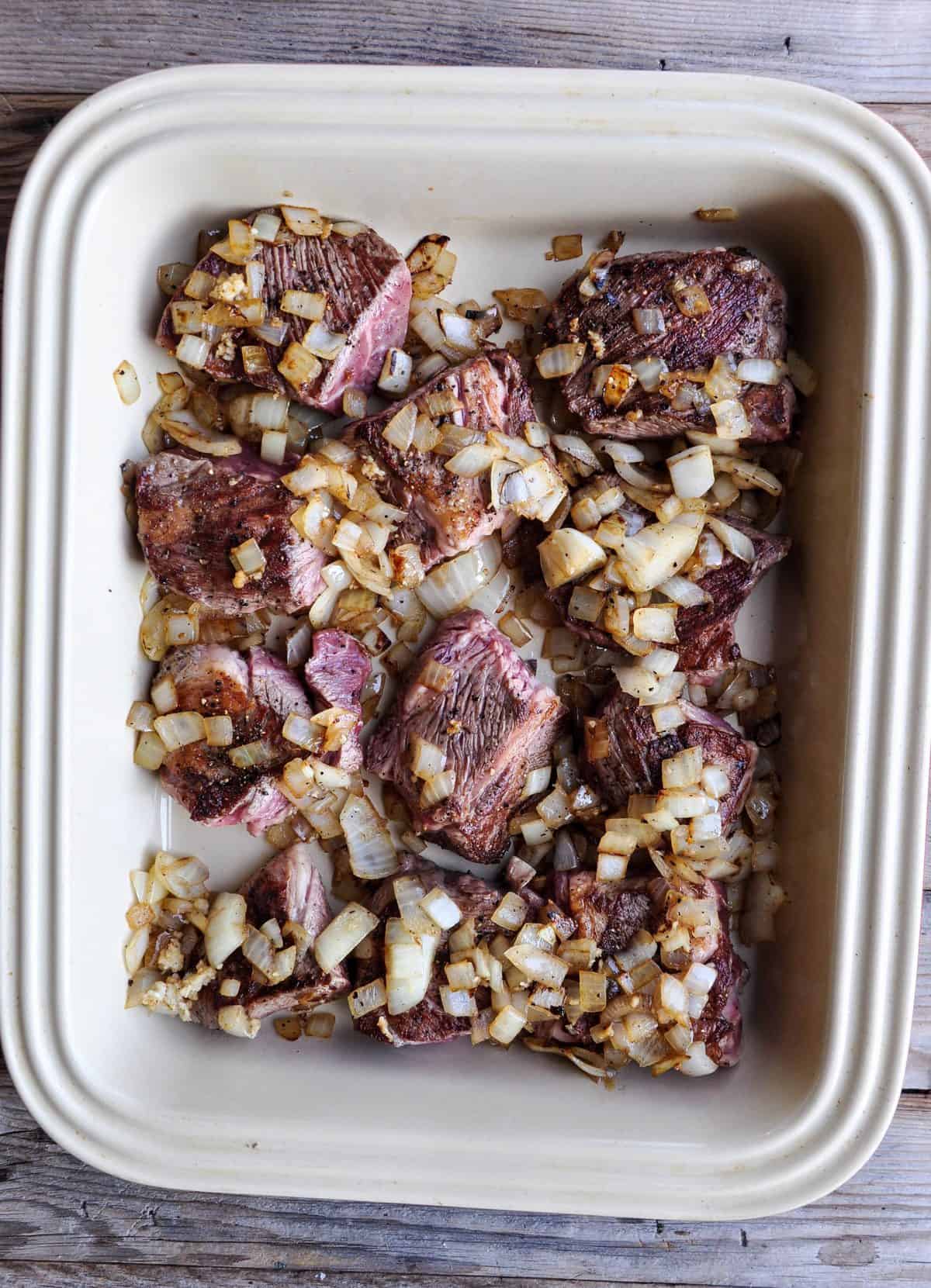 Browned chuck roast with sautéed diced yellow onion and garlic in deep roasting dish