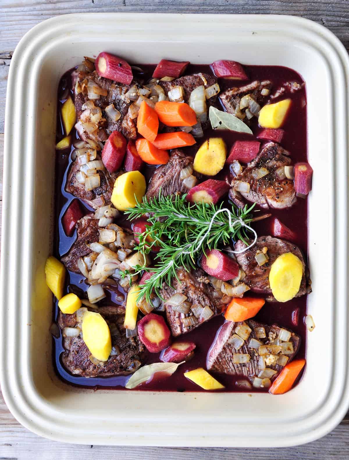 Carrots, fresh herbs and wine broth added to deep baking dish