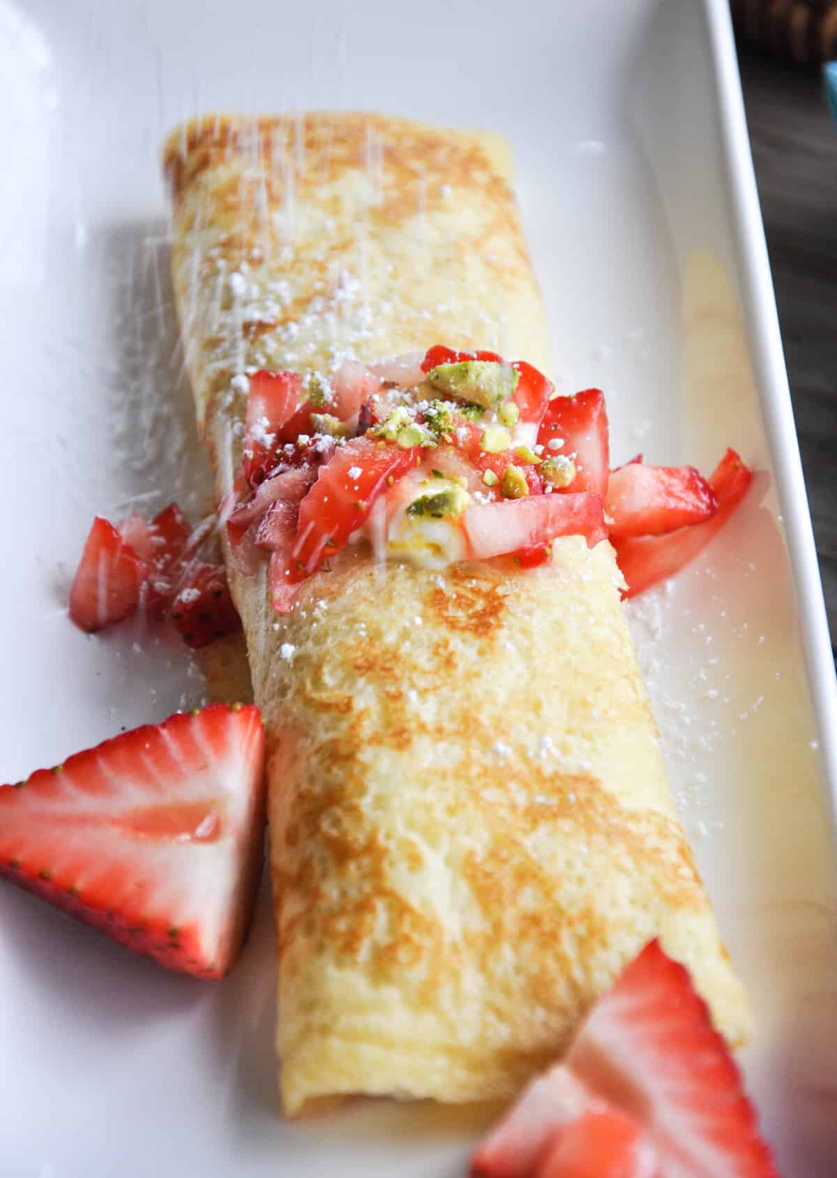 Lemon Crème Crepes with Strawberries and Pistachios topped with Powdered Sugar