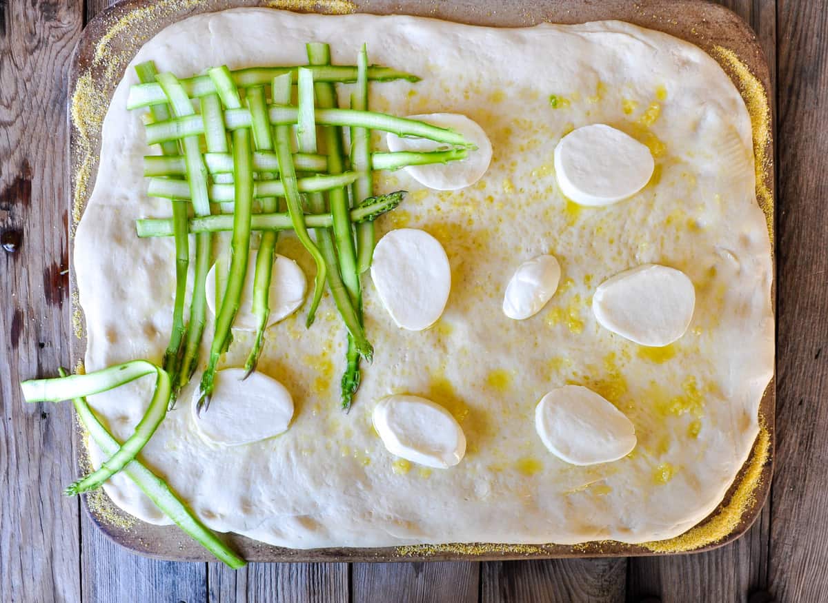 Add cheese and asparagus ribbons to pizza