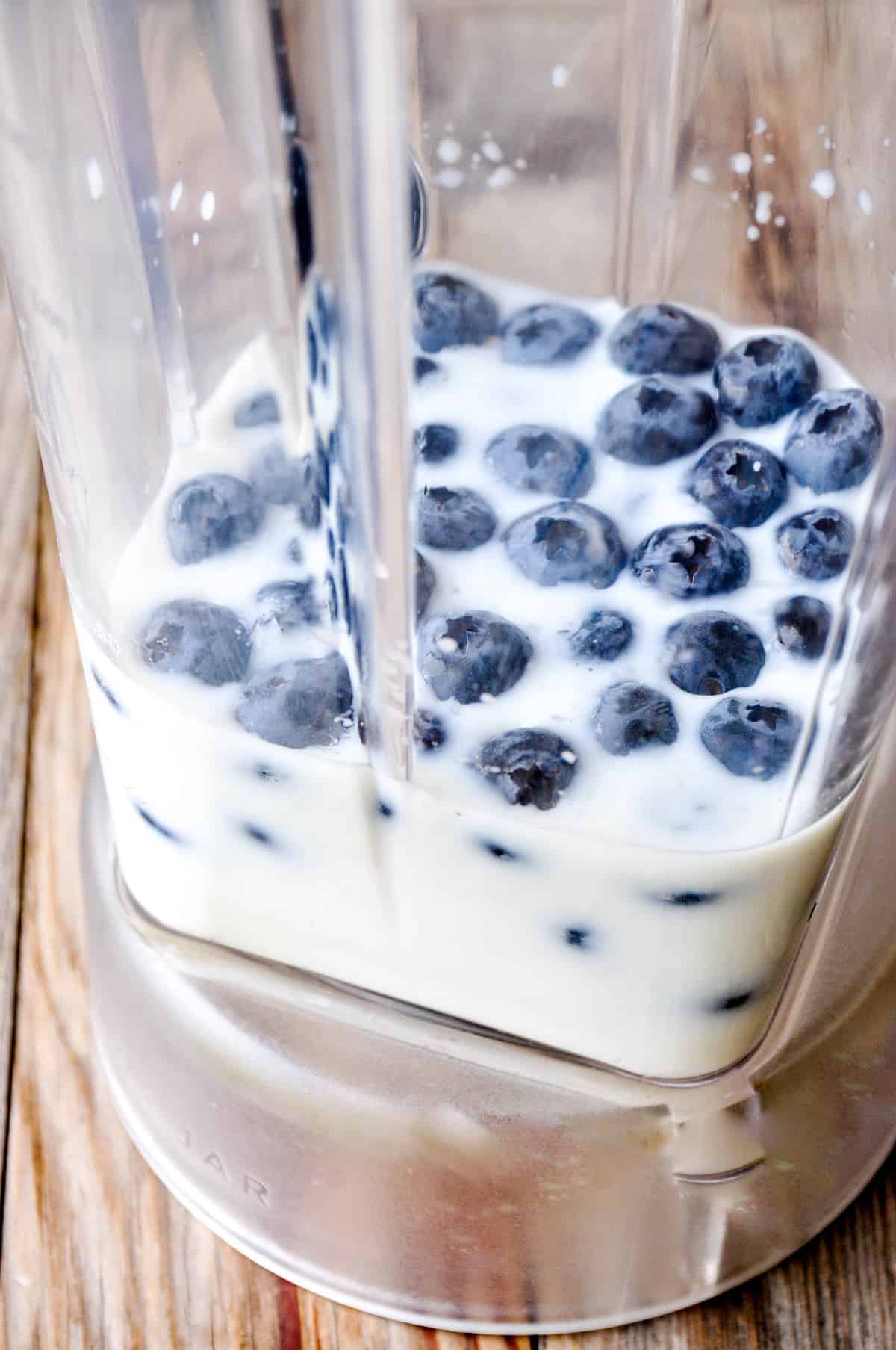 Plain Greek yogurt, milk, and blueberries in blender