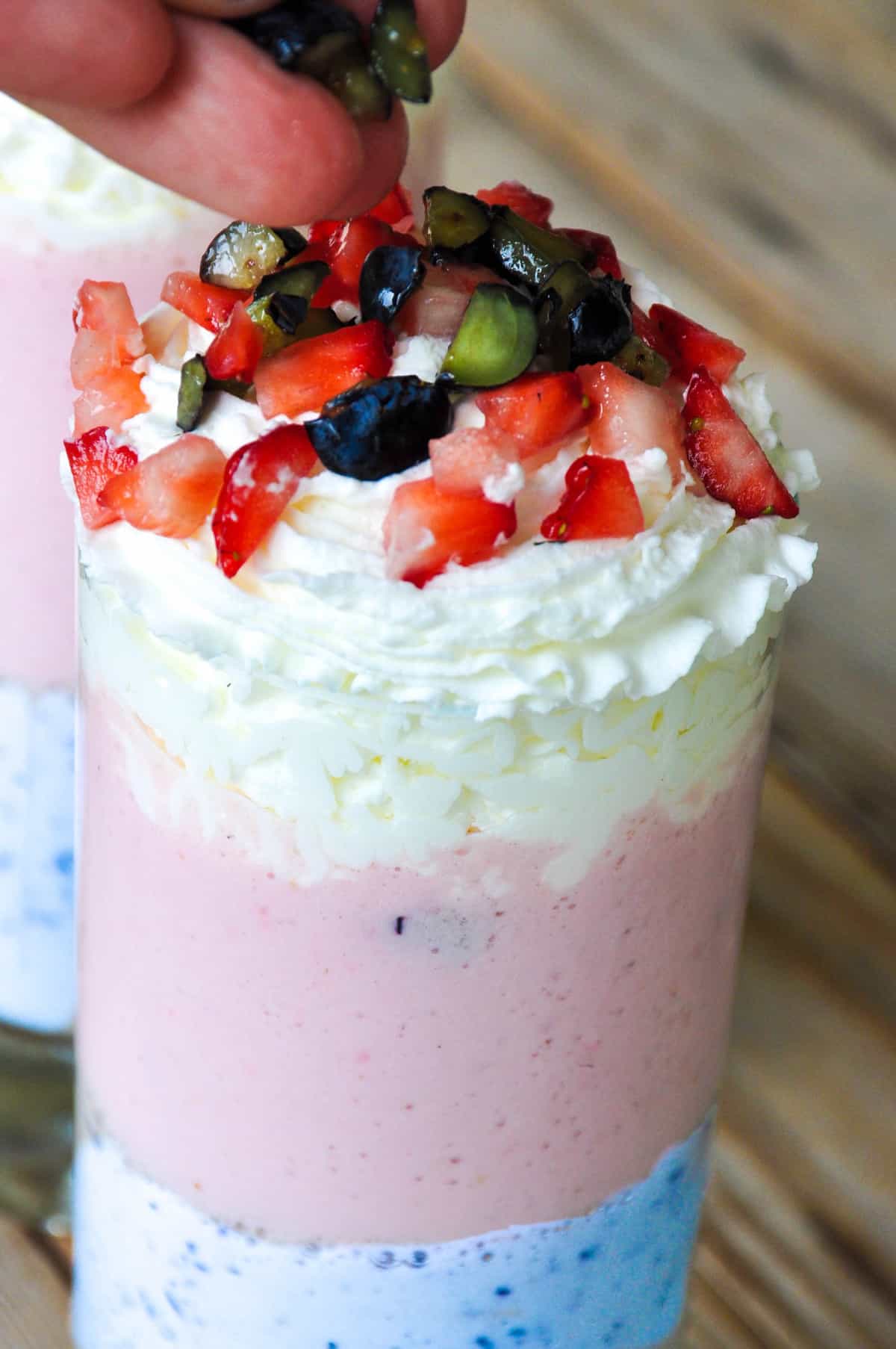 Unicorn smoothie with whipped cream topped with blueberries and strawberries