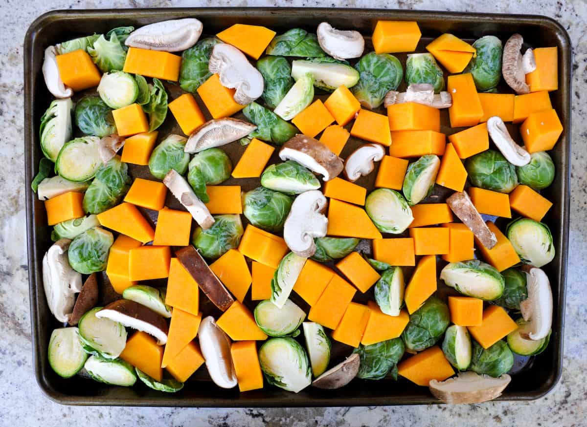 Halved vegetables on baking sheet: Brussels sprouts, mushroom, and butternut squash