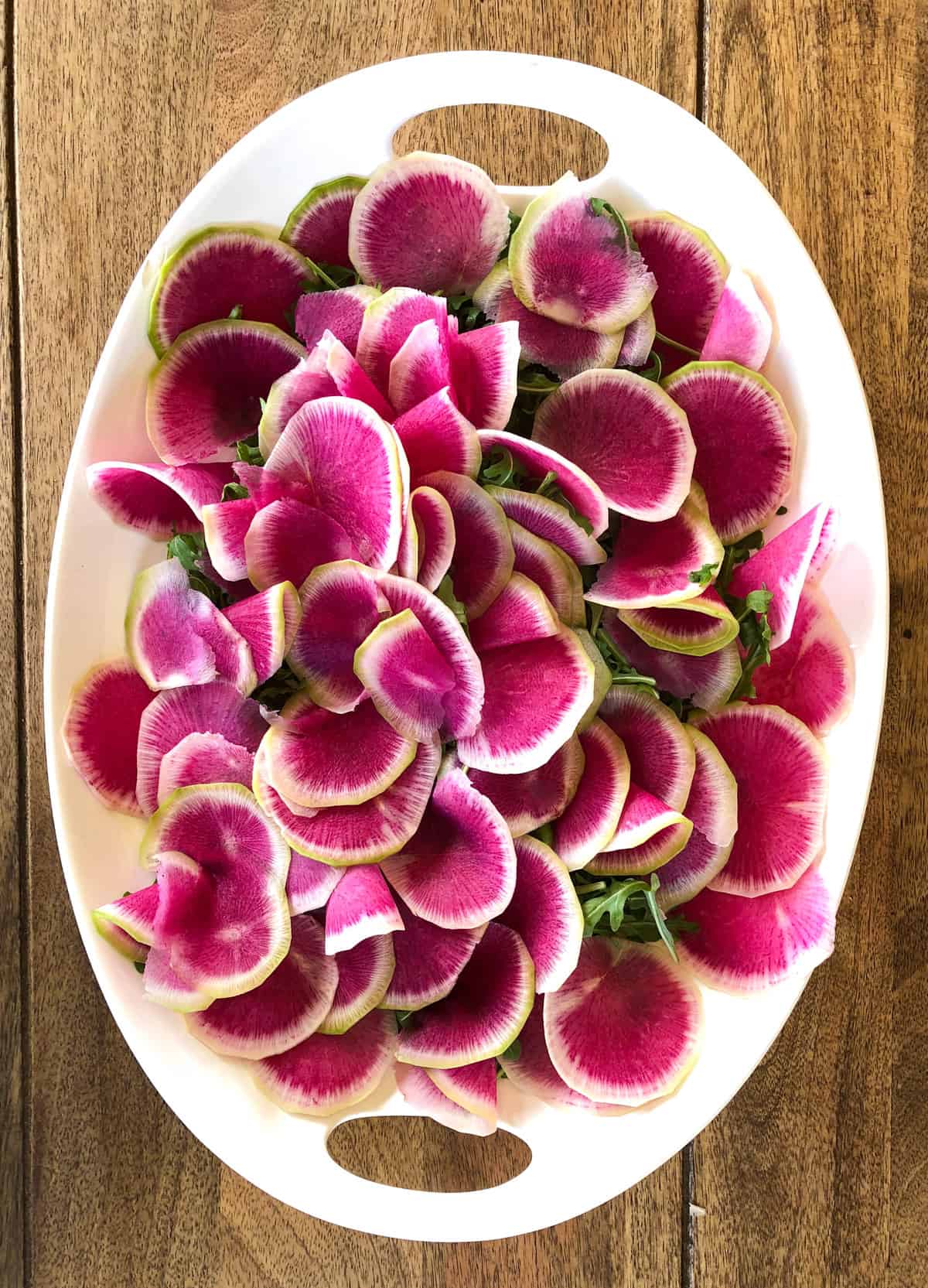 Top arugula base with watermelon radishes 