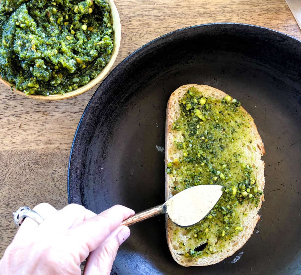 Place buttered side down into a pan and add the Pesto to the bread
