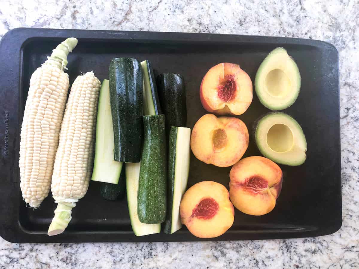 Corn, halved zucchini, halved peaches, and halved avocados