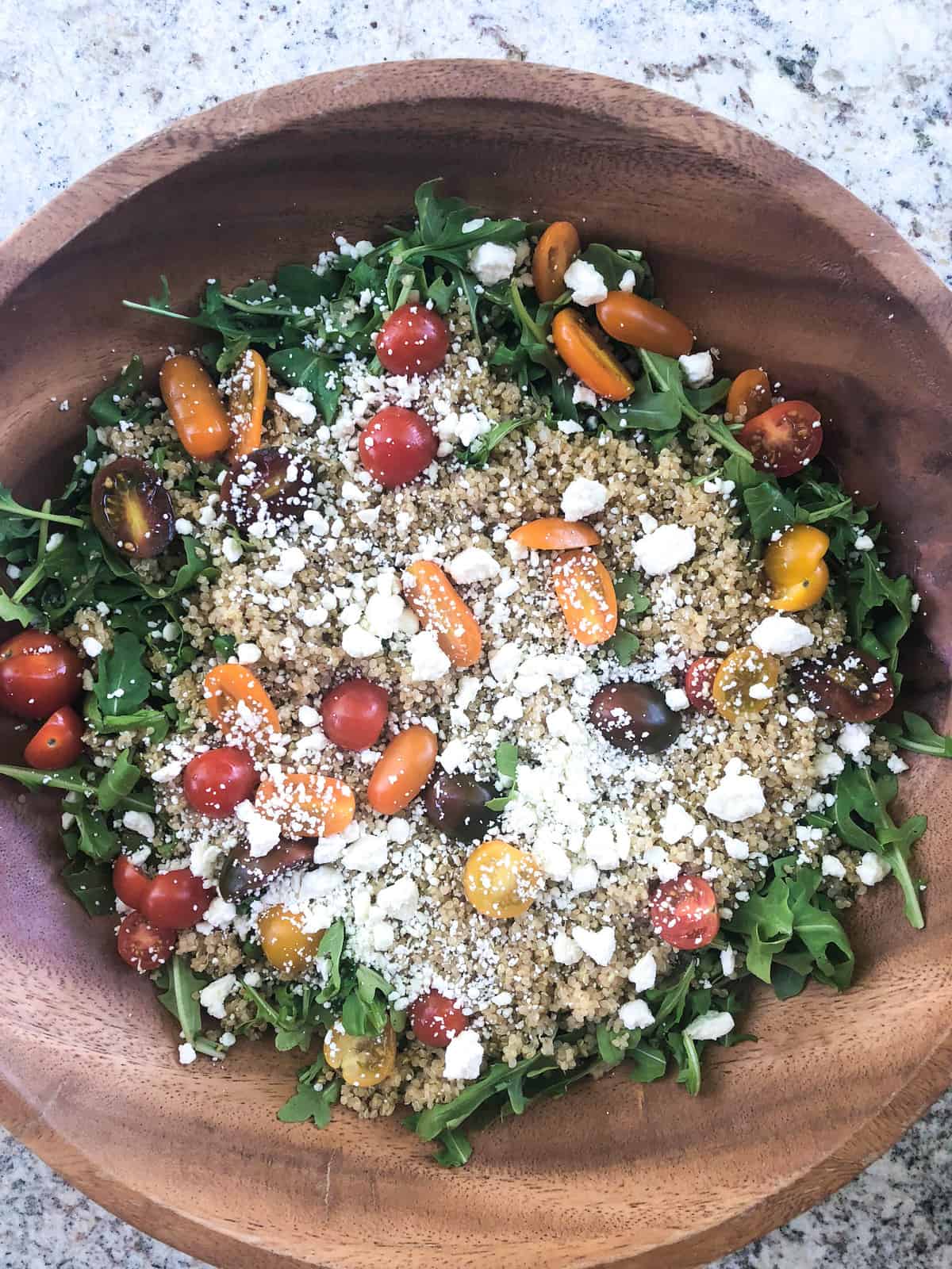 The next layer is feta cheese and halved cherry tomatoes.