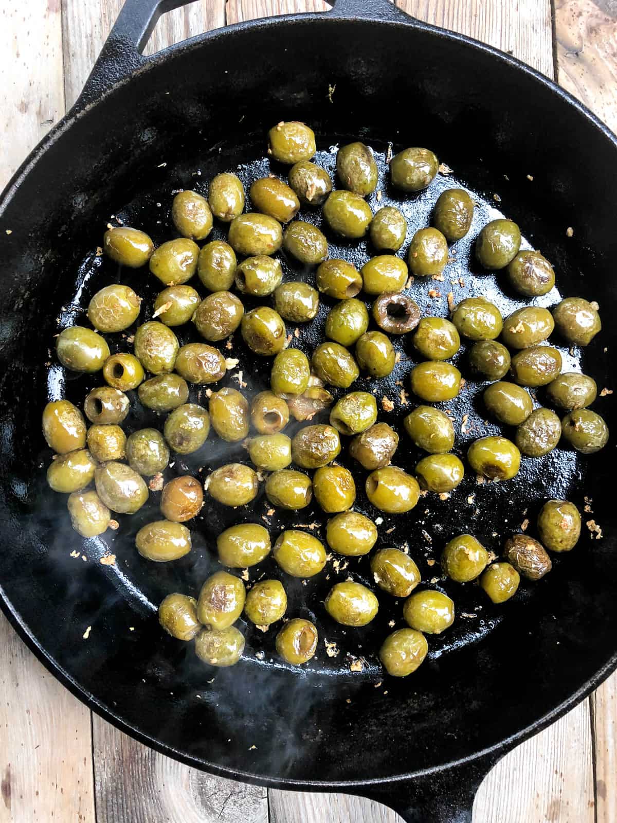 After 5 minutes, the olives should be heated and charred, causing the skins to blister a bit.