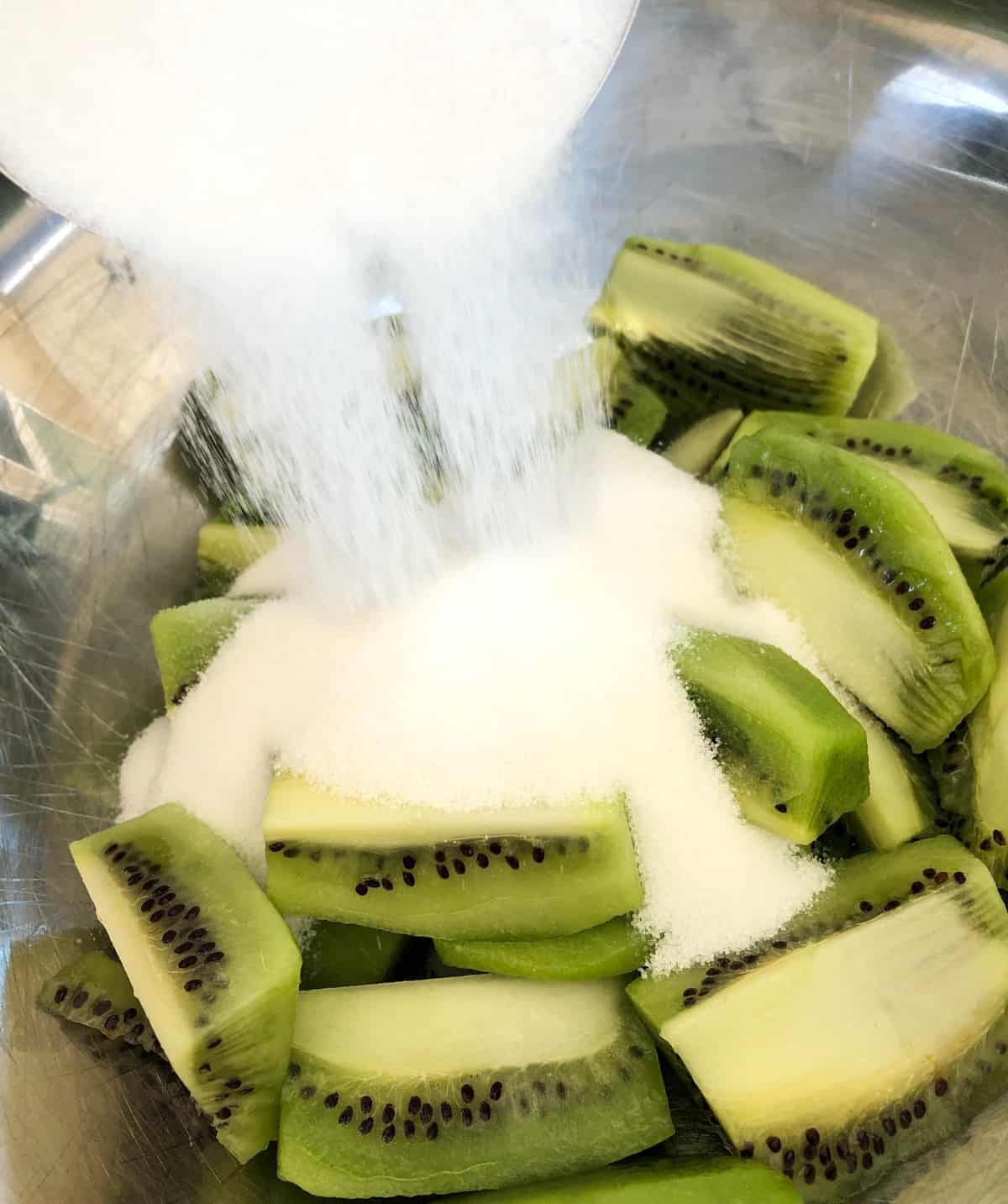 Start by adding the sugar to the peeled and quartered kiwis.