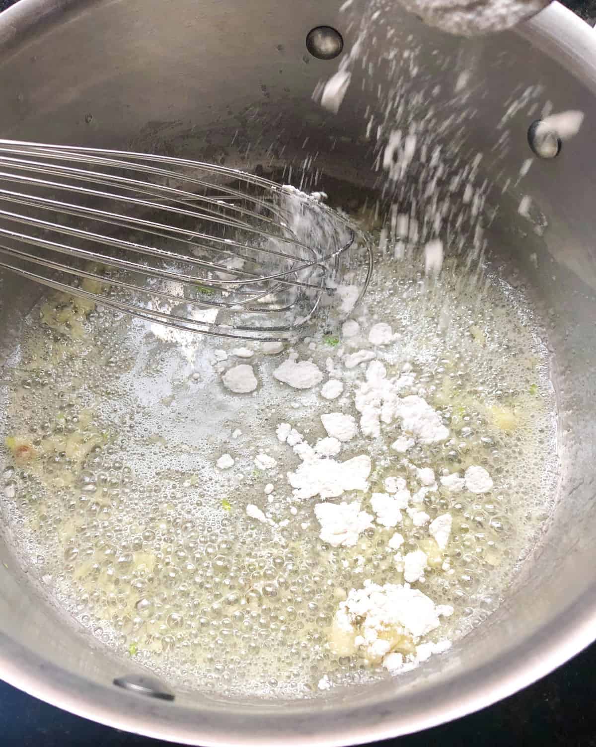 Add the butter and melt over medium heat. Add in the minced garlic and stir for about 15 seconds, then whisk in the remaining flour to start a roux.