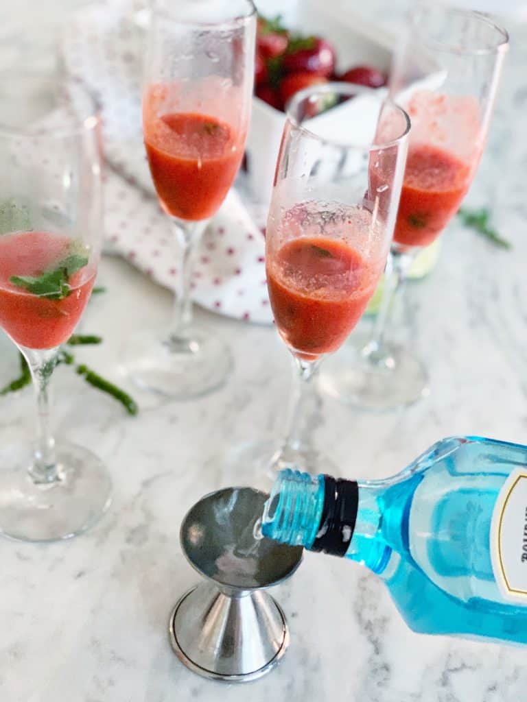 adding gin to a strawberry spritzer cocktail