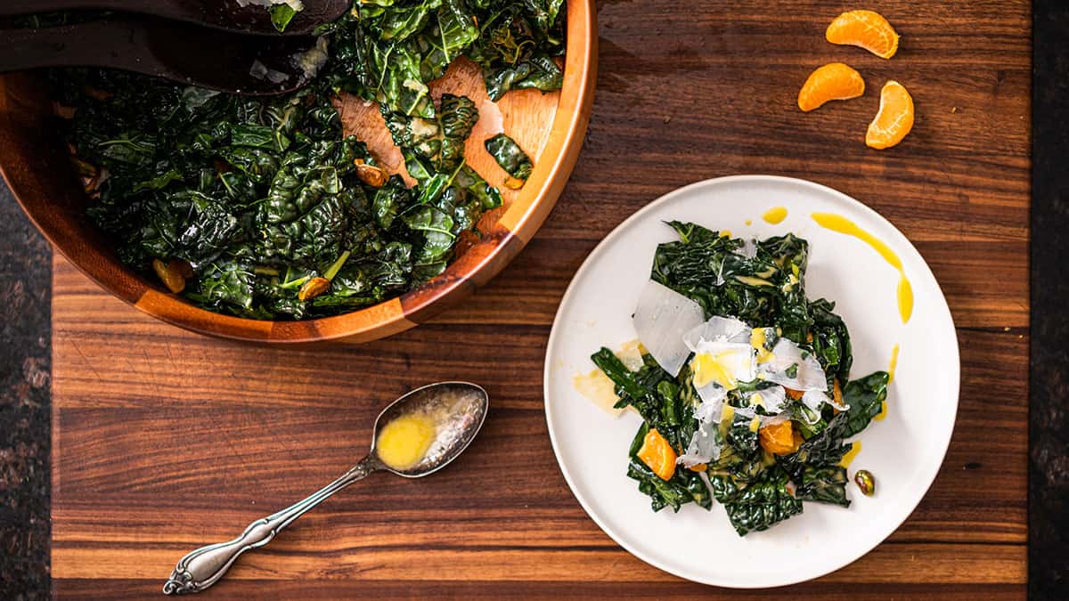 A bowl and plate of Kale, Tangerine, and Pistachio Salad Recipe.