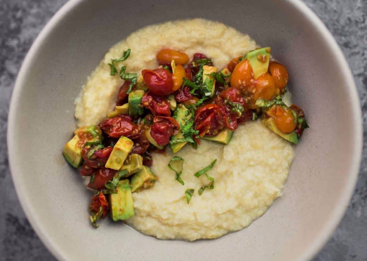 A bowl filled with Sweet Corn Polenta then topped with Roasted Tomatoes and Avocado 