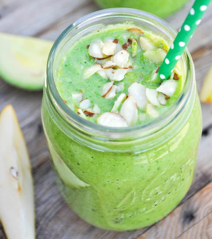 Green Smoothie with Leafy Greens like Spinach and almonds on top.