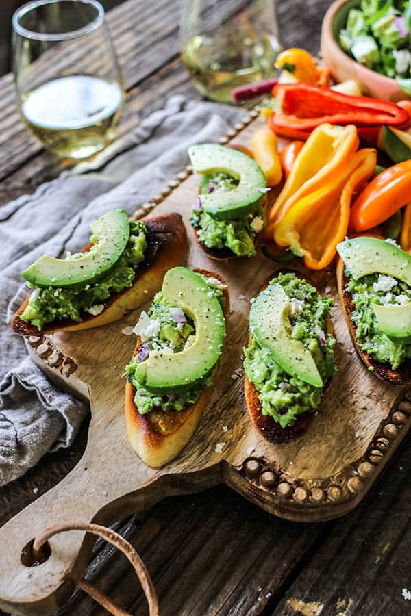 CA Fresh Herb Guacamole with Feta smeared on a toasted baguette and topped with a beautiful slice of avocado.